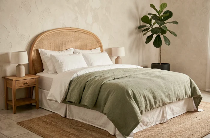 Chambre à coucher élégante avec tête de lit en rotin, literie en lin sauge et décoration naturelle minimaliste